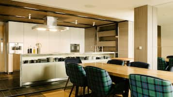 Une cuisine moderne dotée d’un îlot central, de meubles blancs et d’un coin repas avec des chaises à carreaux.