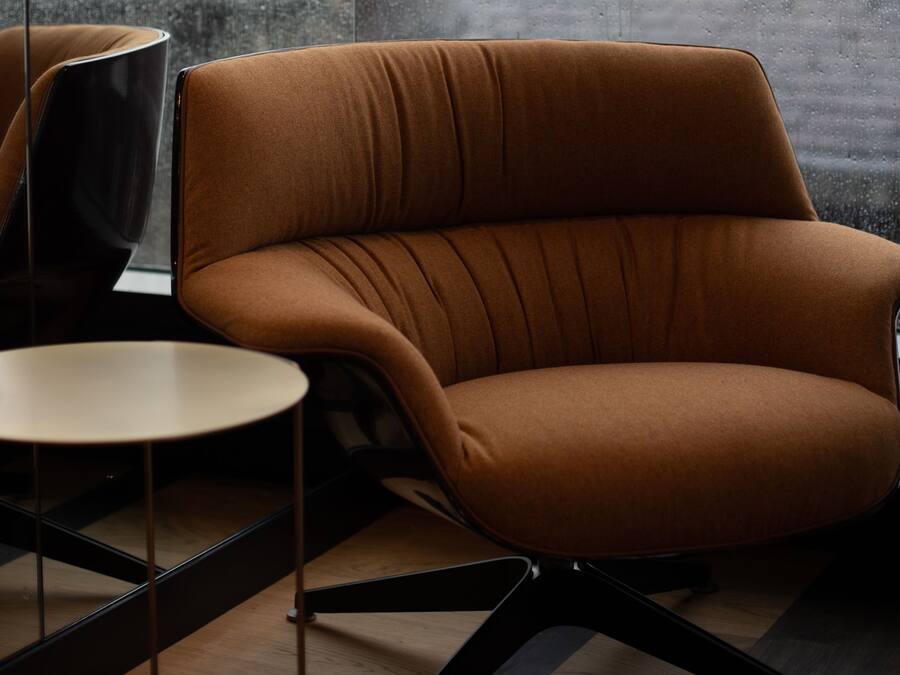 A modern room with a brown upholstered armchair, a small round table, and a black chair.