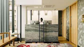 A modern reception area with a marble counter, wooden doors, and a floral rug.