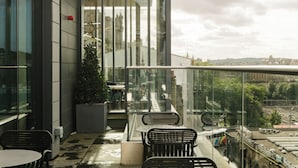 A balcony with seating, a potted plant, and a view of the cityscape. - Market Street Hotel (Edinburgh)