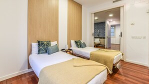 Habitación de hotel con dos camas, paneles de madera y vista al baño.