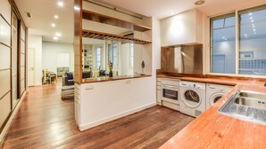 Una cocina moderna con encimera de madera, electrodomésticos integrados y un amplio ventanal.