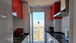Een smalle keuken met uitzicht op een stadsgezicht door een glazen deur.