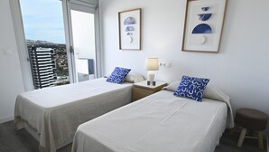 Een hotelkamer met twee bedden, een nachtkastje met een lamp en een wand met ingelijste kunst.