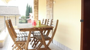 A wooden table with four chairs on a balcony with stone walls and a tiled floor. - Il Papavero apartment Sirmione | Terme & Garda Lake (Sirmione)