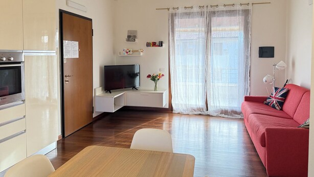 A compact living space with a kitchenette, a dining area, and a living room with a sofa and a TV. - Il Papavero apartment Sirmione | Terme & Garda Lake (Sirmione)