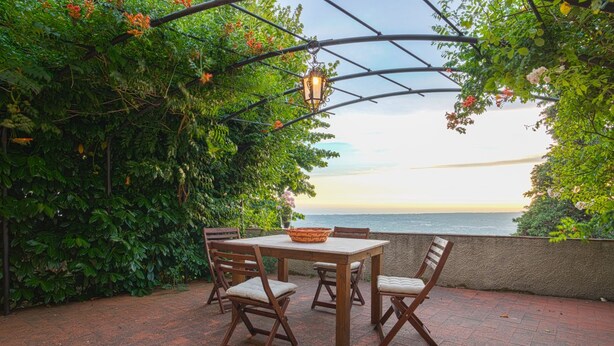 An outdoor patio with a table and chairs, a basket, and a view of the sea. - Santa Lucia Suite, Lovely View Over the Shore.. (Camaiore)