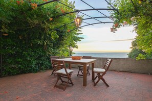 An outdoor patio with a table and chairs, a basket, and a view of the sea. - Santa Lucia Suite, Lovely View Over the Shore.. (Camaiore)