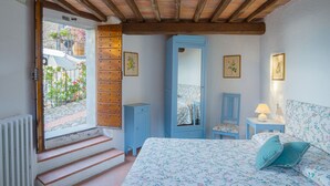A bedroom with a bed, a dresser, a mirror, and a window with a view of a street and greenery. - Santa Lucia Suite, Lovely View Over the Shore.. (Camaiore)