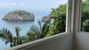 A view from a window overlooking a coastal landscape with a large island and calm sea.