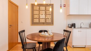A dining area with a wooden table, black chairs, a framed picture on the wall, and a kitchen area with a sink and cabinets. - Very Nice Decorated 2 Bedroom Apartment (Oporto)