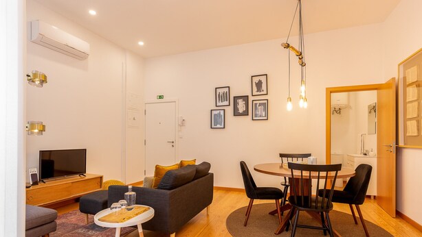 A modern living room with a sofa, TV, dining table, and chairs. - Very Nice Decorated 2 Bedroom Apartment (Oporto)
