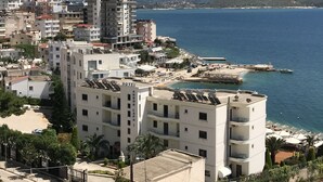 A coastal hotel with multiple floors, a beachside location, and a view of the sea and mountains in the background. - Bella Apartment for rent near to the beach Sarandë , Albania  (Saranda)