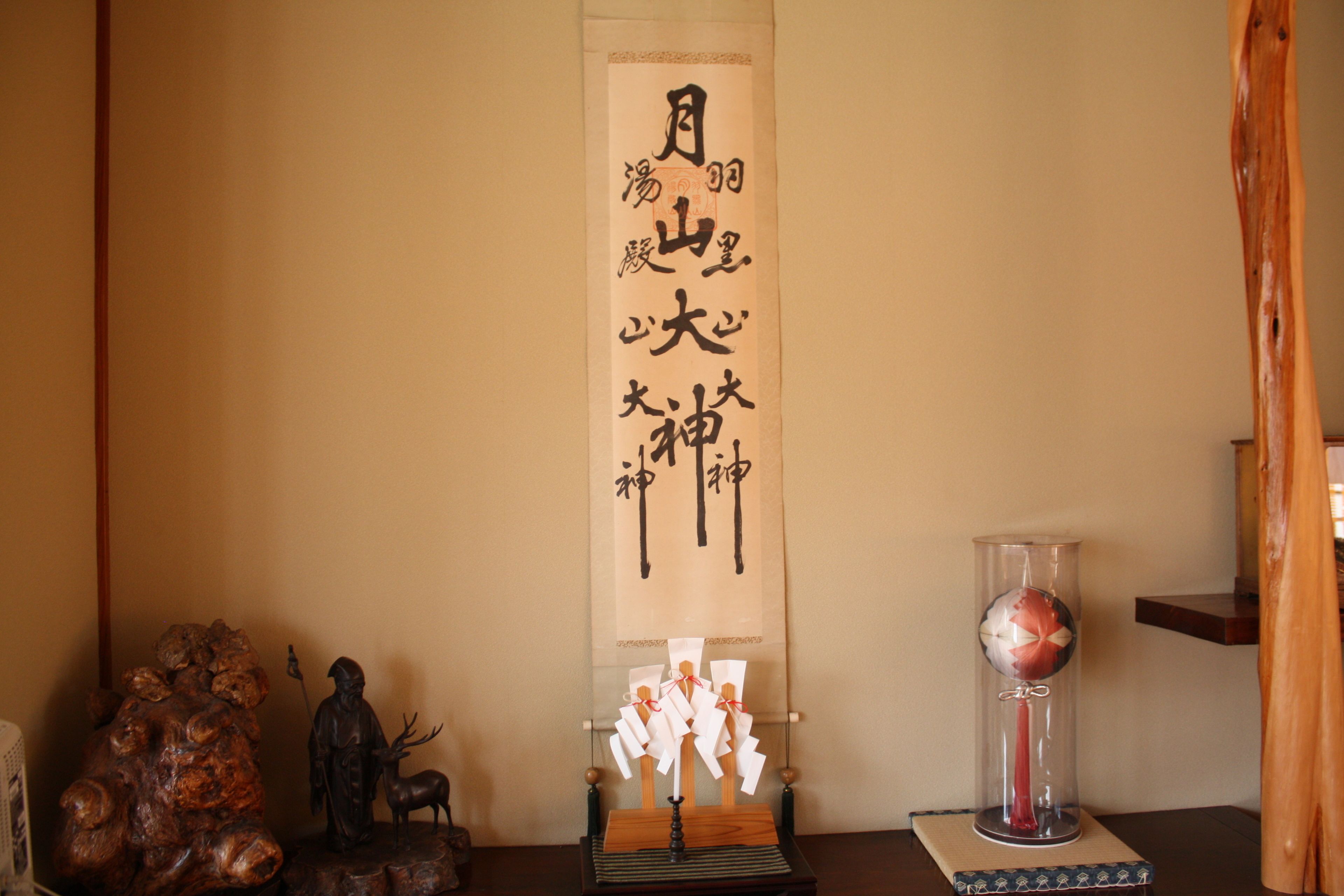 Una habitación japonesa tradicional con un rollo de caligrafía, una escultura de madera y un florero de cristal.