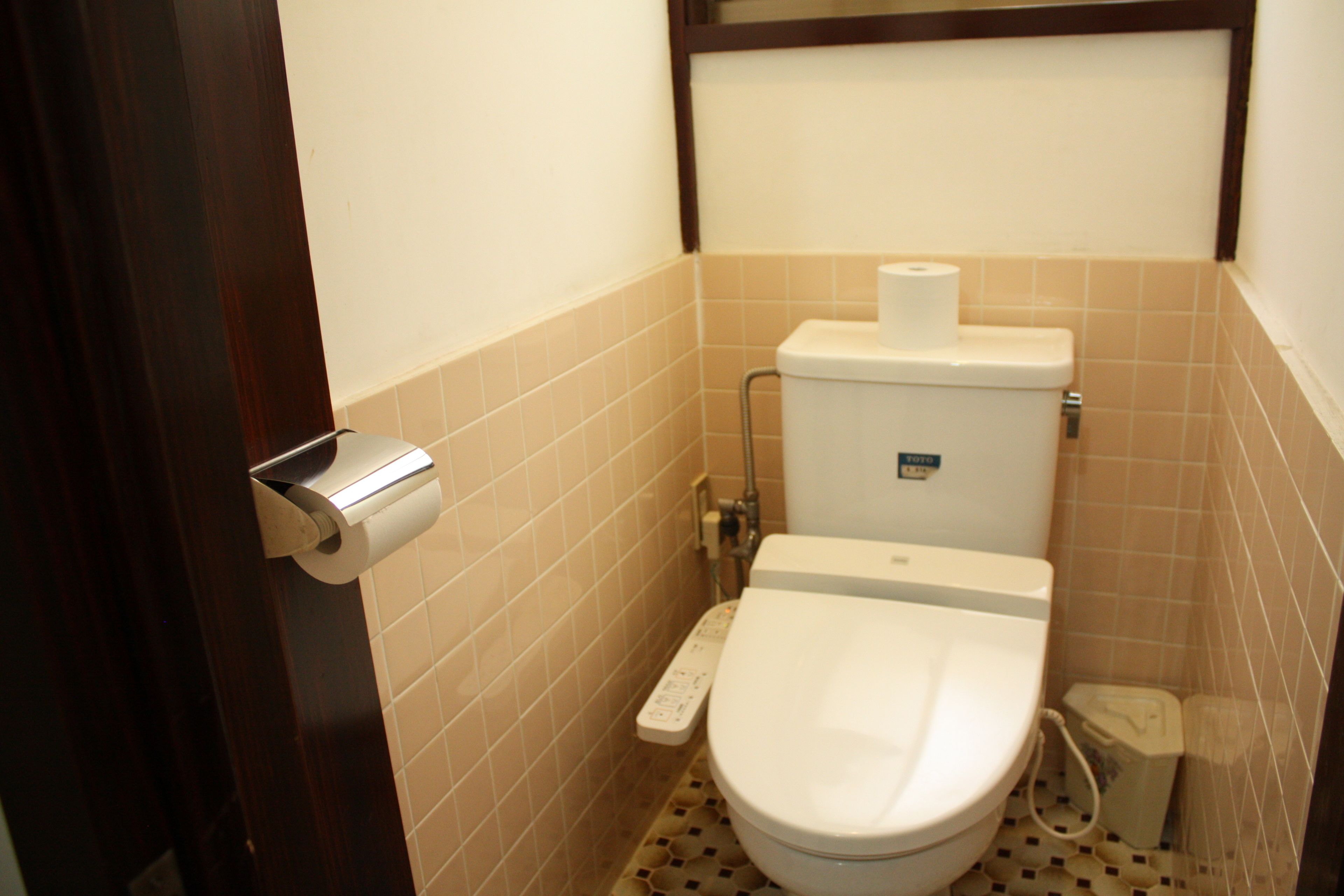 A small bathroom with a toilet, a paper towel dispenser, and a toilet paper holder.