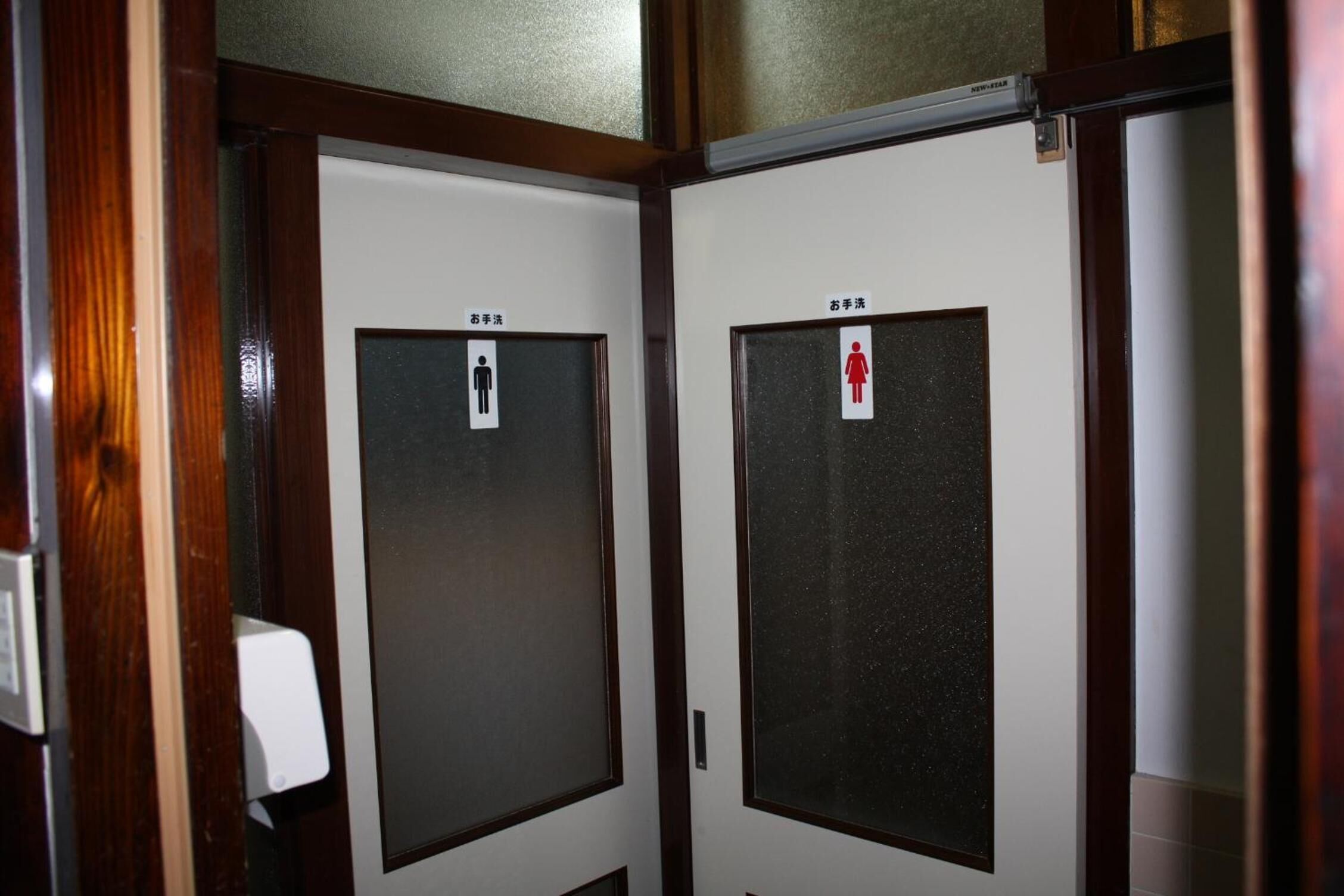 A doorway leading to a restroom with a sign indicating a men's and a women's room.