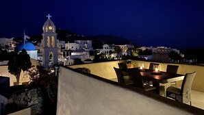 A rooftop terrace with a table and chairs, overlooking a town with white buildings and a prominent church with a blue dome. - Mansion Kyani- Spectacular Santorini villa- Car included- Private & Spacious (Santorini)