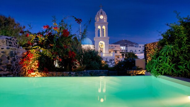 A swimming pool with a view of a white building with a clock tower and a dome in the background. - Mansion Kyani- Spectacular Santorini villa- Car included- Private & Spacious (Santorini)