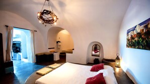 A spacious bedroom with a large bed, a chandelier, and a painting on the wall. - Mansion Kyani- Spectacular Santorini villa- Car included- Private & Spacious (Santorini)