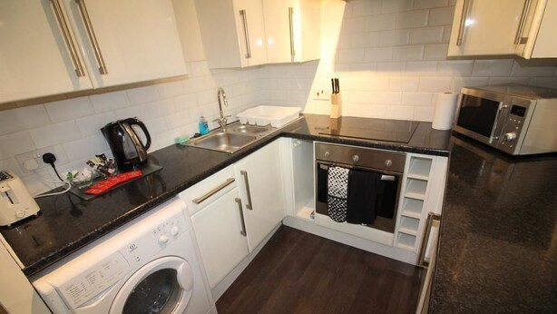 A compact kitchen with a washing machine, a microwave, and a sink.