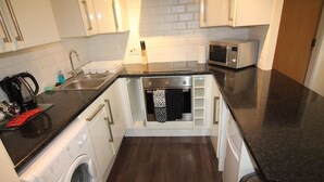 A compact kitchen with a washing machine, microwave, and a small sink.