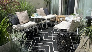 A patio with outdoor furniture, including a sofa and chairs, a small table, and a decorative lantern. - Best deal in town ! Como Designer Apt deluxe in the center of Munich (Munich)