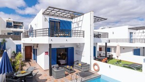 A two-story building with a pool, outdoor seating, and a balcony. - Air-conditioned Villa With Mountain Views, 300m From Coastal Path - Villa Elise (playa blanca)