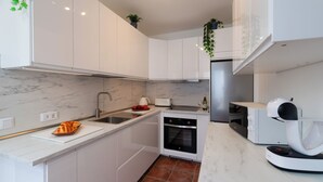 A modern kitchen with white cabinets, a marble countertop, a built-in oven, a coffee machine, and a sink. - Air-conditioned Villa With Mountain Views, 300m From Coastal Path - Villa Elise (playa blanca)