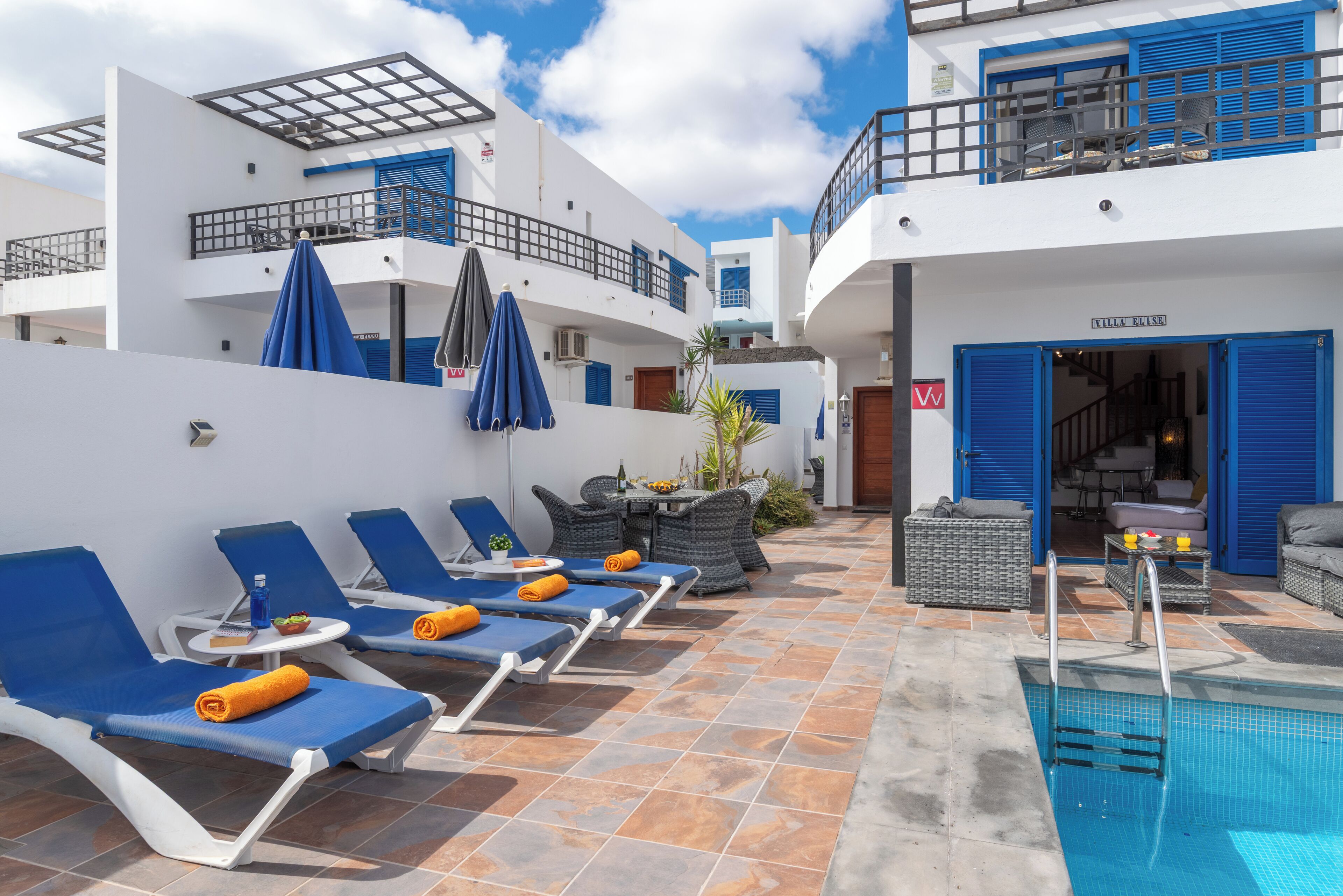 A poolside area with lounge chairs, umbrellas, and a pool.