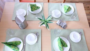 A table set for four with green patterned napkins, white plates, and silverware. - Pension Leonardo (Aidenbach)