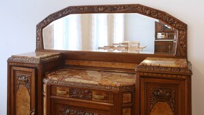 A wooden vanity with a large mirror, intricate carvings, and a marble countertop. - Pension Leonardo (Aidenbach)