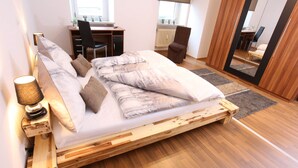 A bedroom with a wooden bed, a desk, a chair, and a mirror. - Pension Leonardo (Aidenbach)