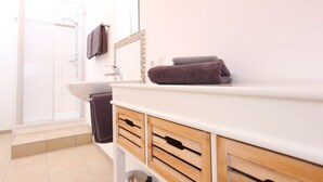 A bathroom with a white sink, wooden cabinets, and a shower area. - Pension Leonardo (Aidenbach)