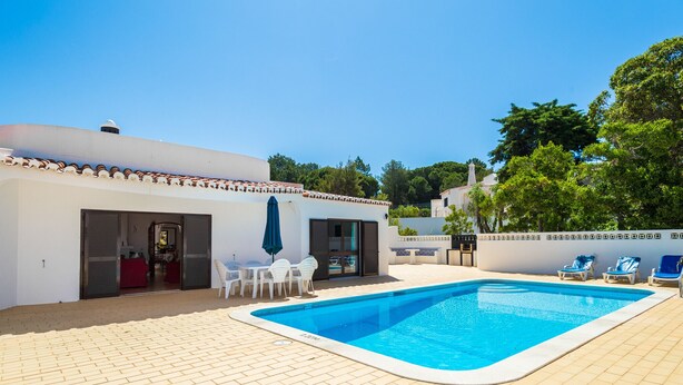 A swimming pool with a tiled deck, a covered seating area, and a building with a tiled roof. - Casa dos Caes - Private pool, just 500m from golf course & 1.5km from beach (Carvoeiro)