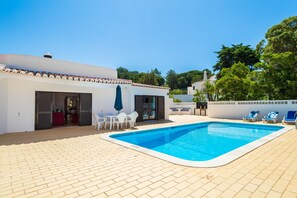 A swimming pool with a tiled deck, a covered seating area, and a building with a tiled roof. - Casa dos Caes - Private pool, just 500m from golf course & 1.5km from beach (Carvoeiro)