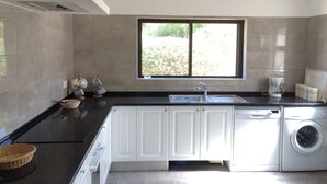 A modern kitchen with a built-in dishwasher, a sink, and a window providing natural light. - Casa dos Caes - Private pool, just 500m from golf course & 1.5km from beach (Carvoeiro)