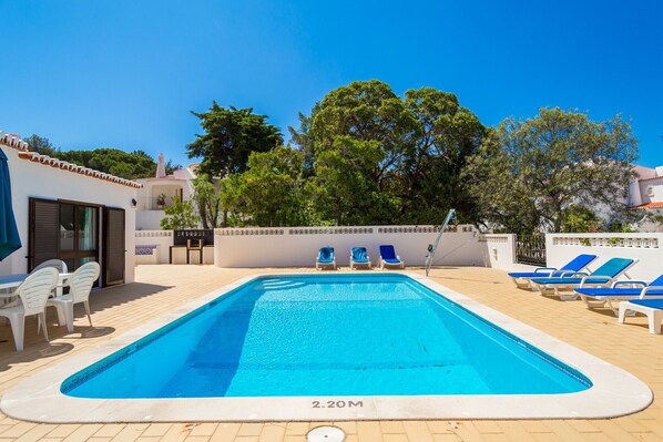 A rectangular swimming pool with a depth marker of 2.20 meters, surrounded by lounge chairs and a small table with chairs. - Casa dos Caes - Private pool, just 500m from golf course & 1.5km from beach (Carvoeiro)
