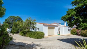 A white building with a red-tiled roof, surrounded by greenery and a gravel driveway. - Casa dos Caes - Private pool, just 500m from golf course & 1.5km from beach (Carvoeiro)