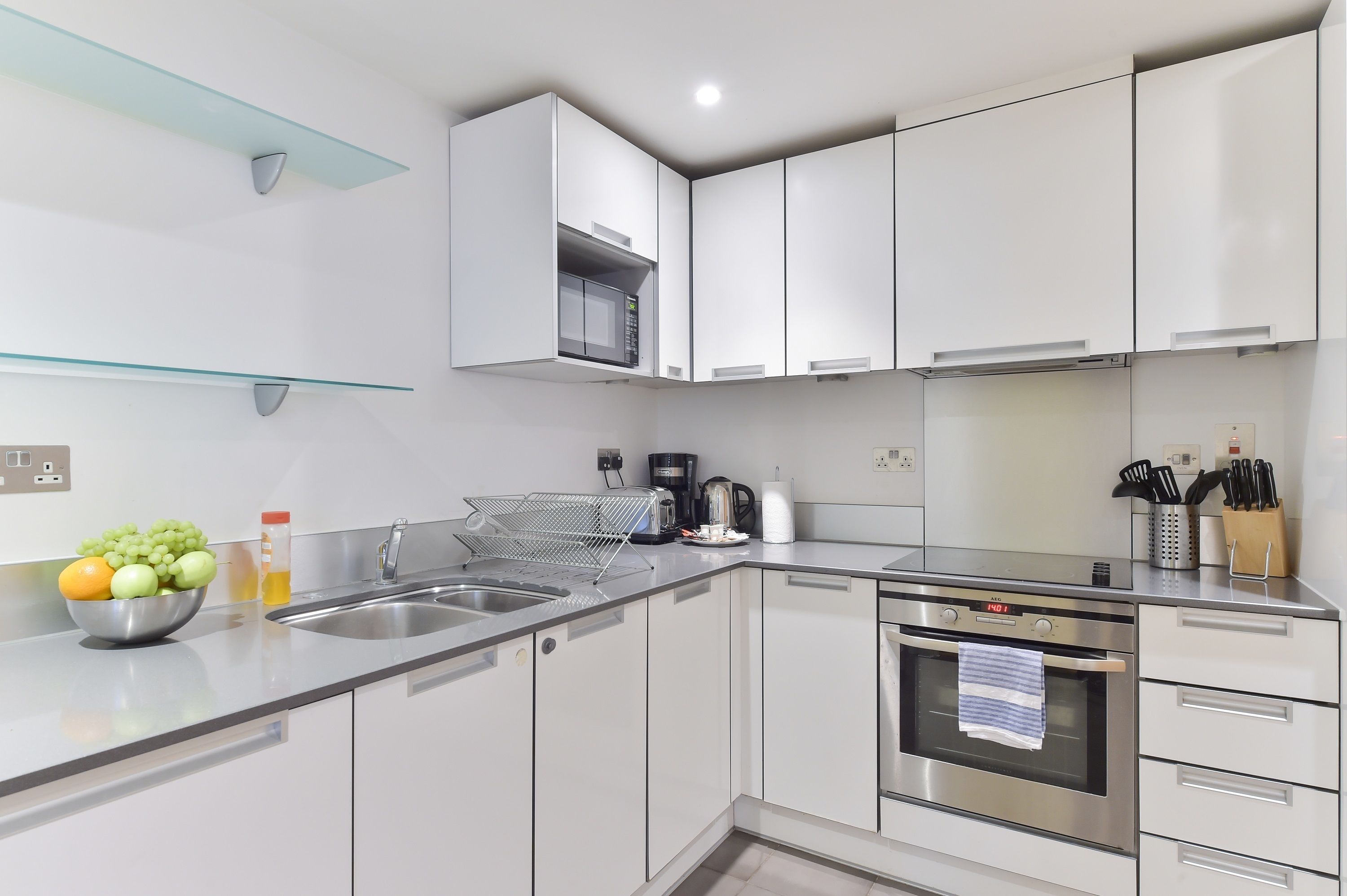 A modern kitchen with white cabinets, stainless steel appliances, and a bowl of fruit on the counter.