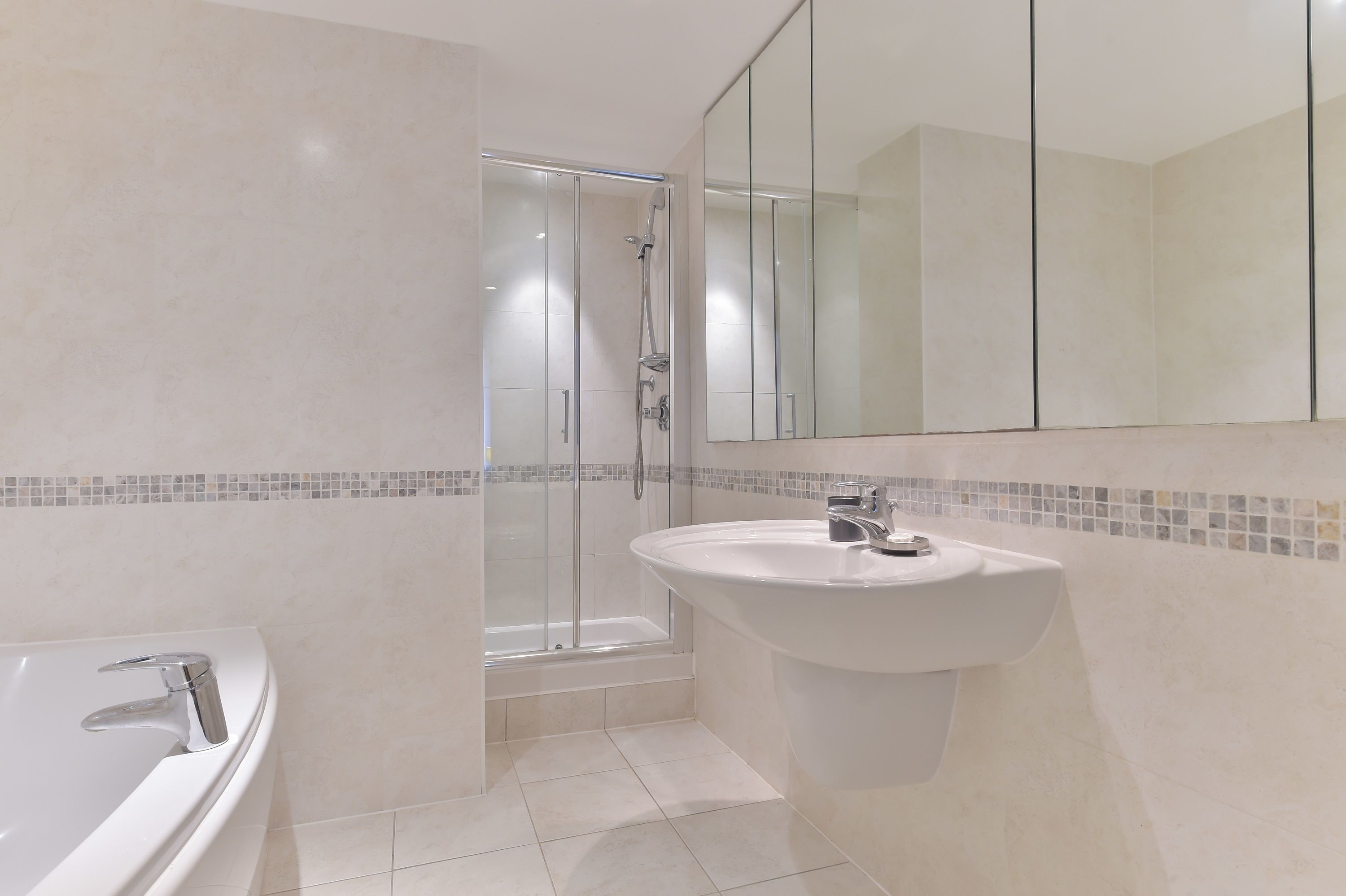 A modern bathroom with a glass-enclosed shower, a freestanding bathtub, and a pedestal sink.
