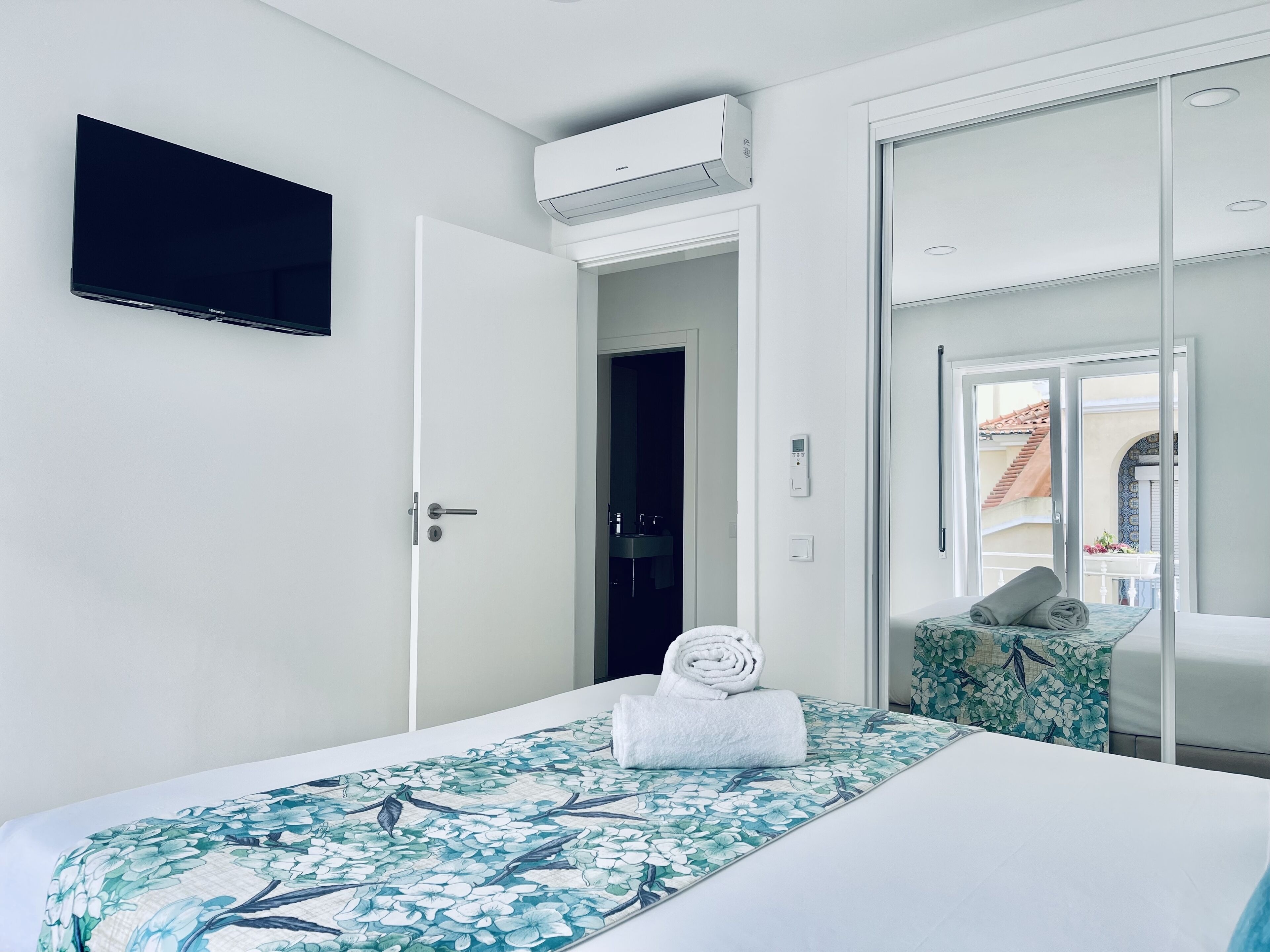Ein Hotelzimmer mit Bett, Fernseher, Klimaanlage, Bad und Blick nach außen.