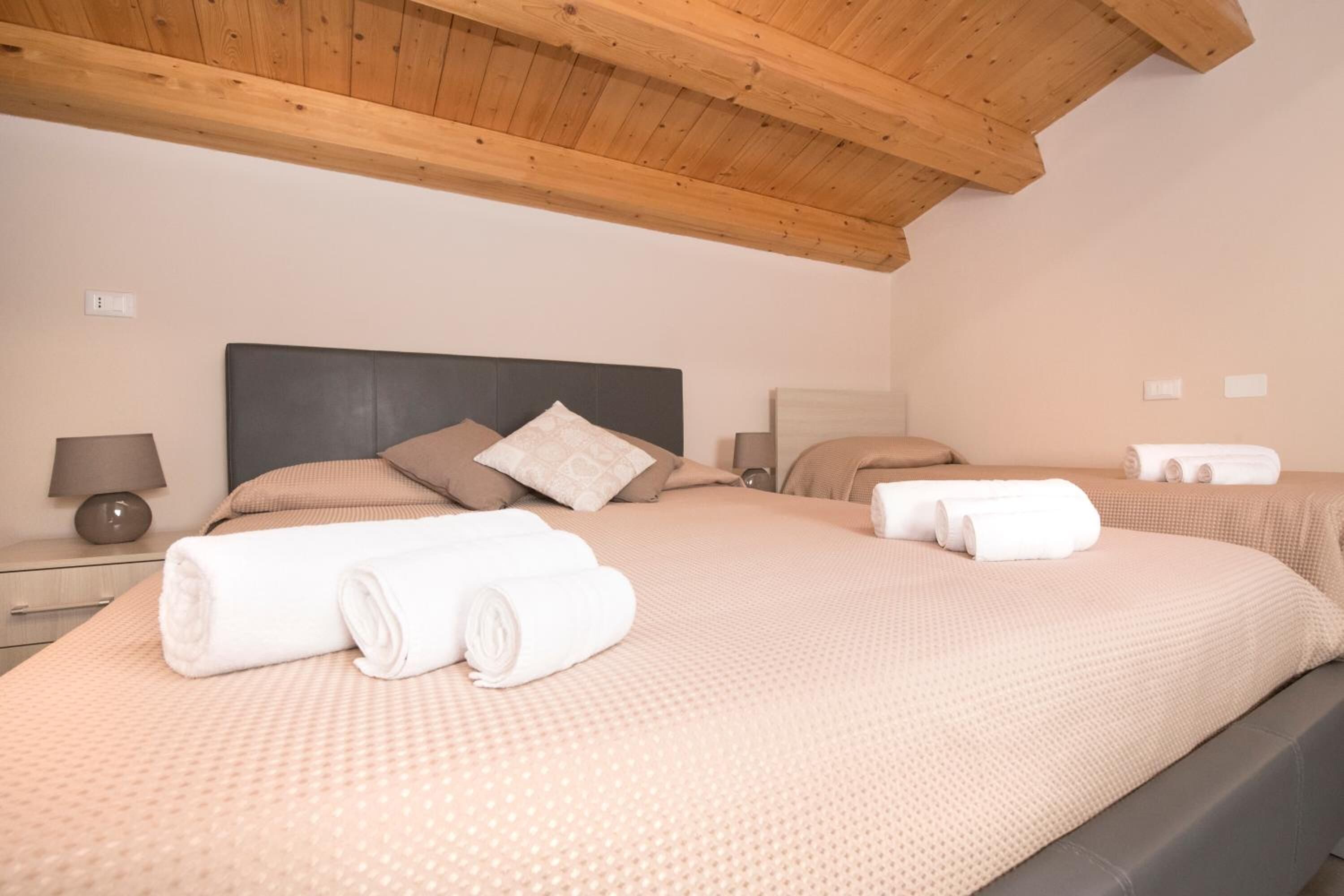 Ein Hotelzimmer mit zwei Betten, Holzbalkendecke und ordentlich gefalteten Handtüchern auf den Betten.
