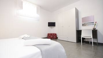 Une chambre moderne comprenant un lit, une télévision, une armoire et un bureau avec une chaise.
