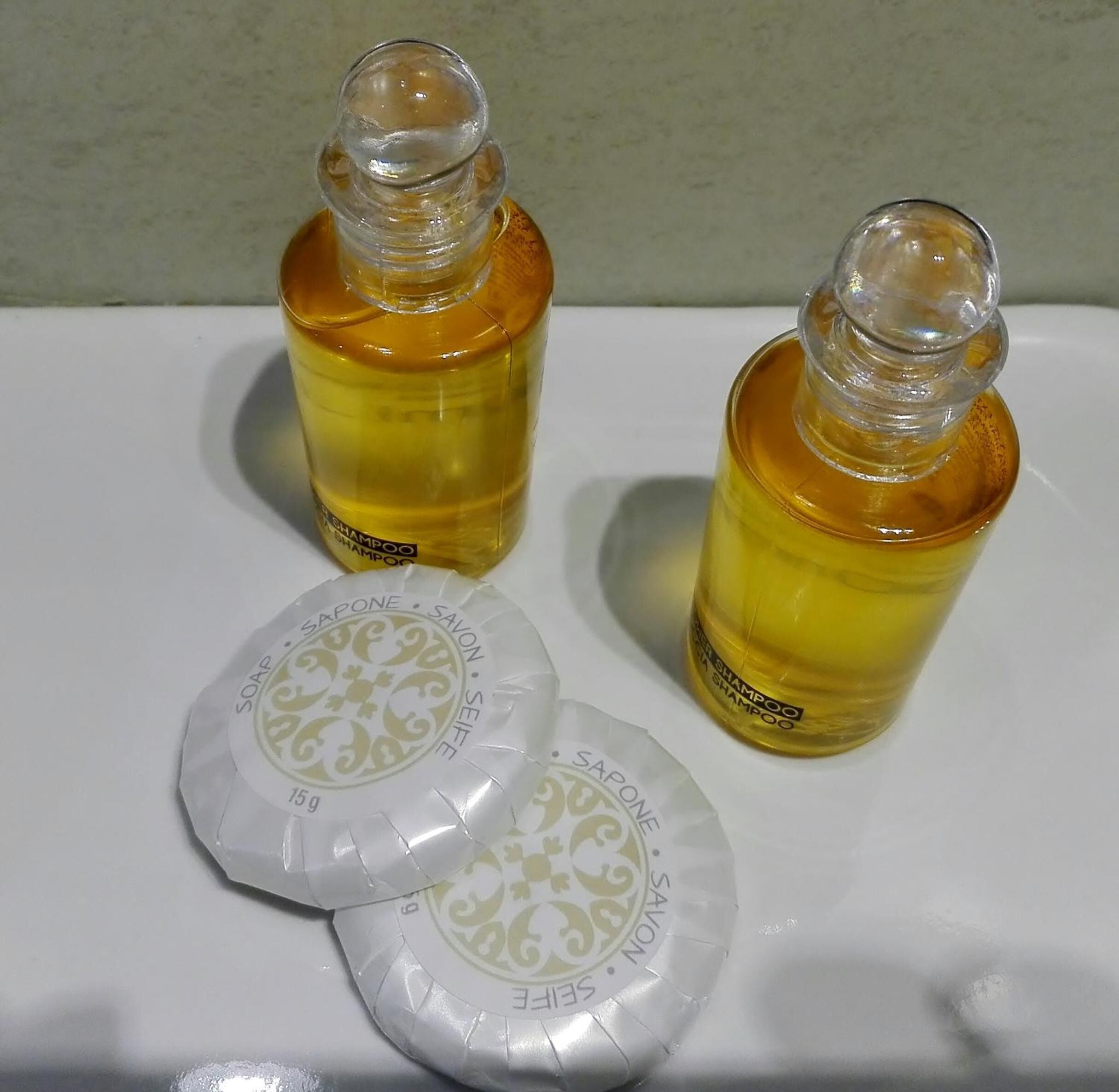 Two bottles of shampoo and two soap bars on a white surface.