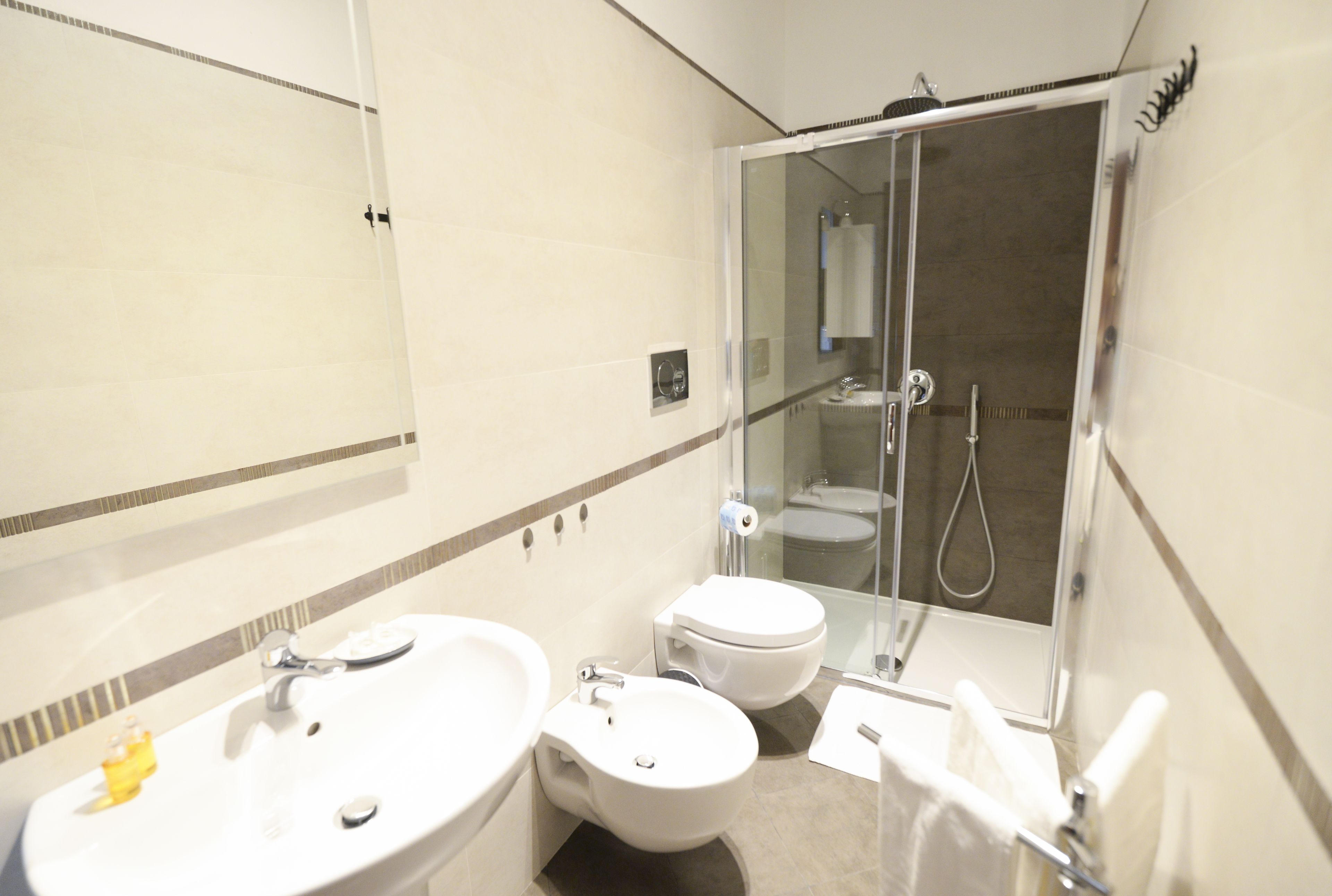 A modern bathroom with a sink, bidet, toilet, and glass-enclosed shower.