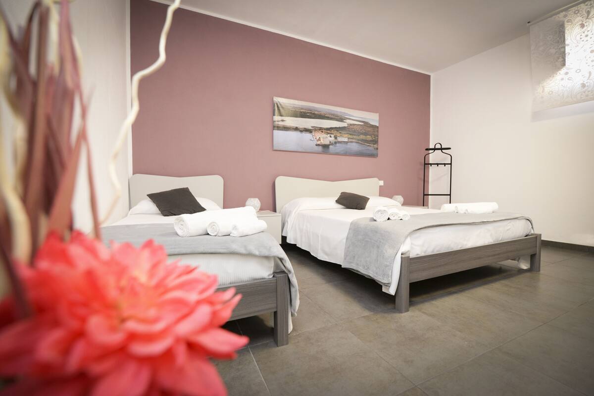 Een hotelkamer met twee bedden, een schilderij aan de muur en een metalen rek.