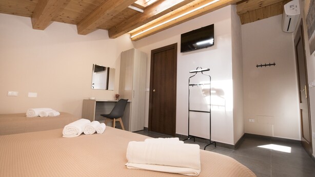 Ein Hotelzimmer mit Bett, Schreibtisch, Stuhl, Spiegel und Duschbereich.