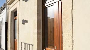 Ein Gebäude mit Holztür und Metallgitter, ein Schild über der Tür und ein Fenster mit Vorhang.