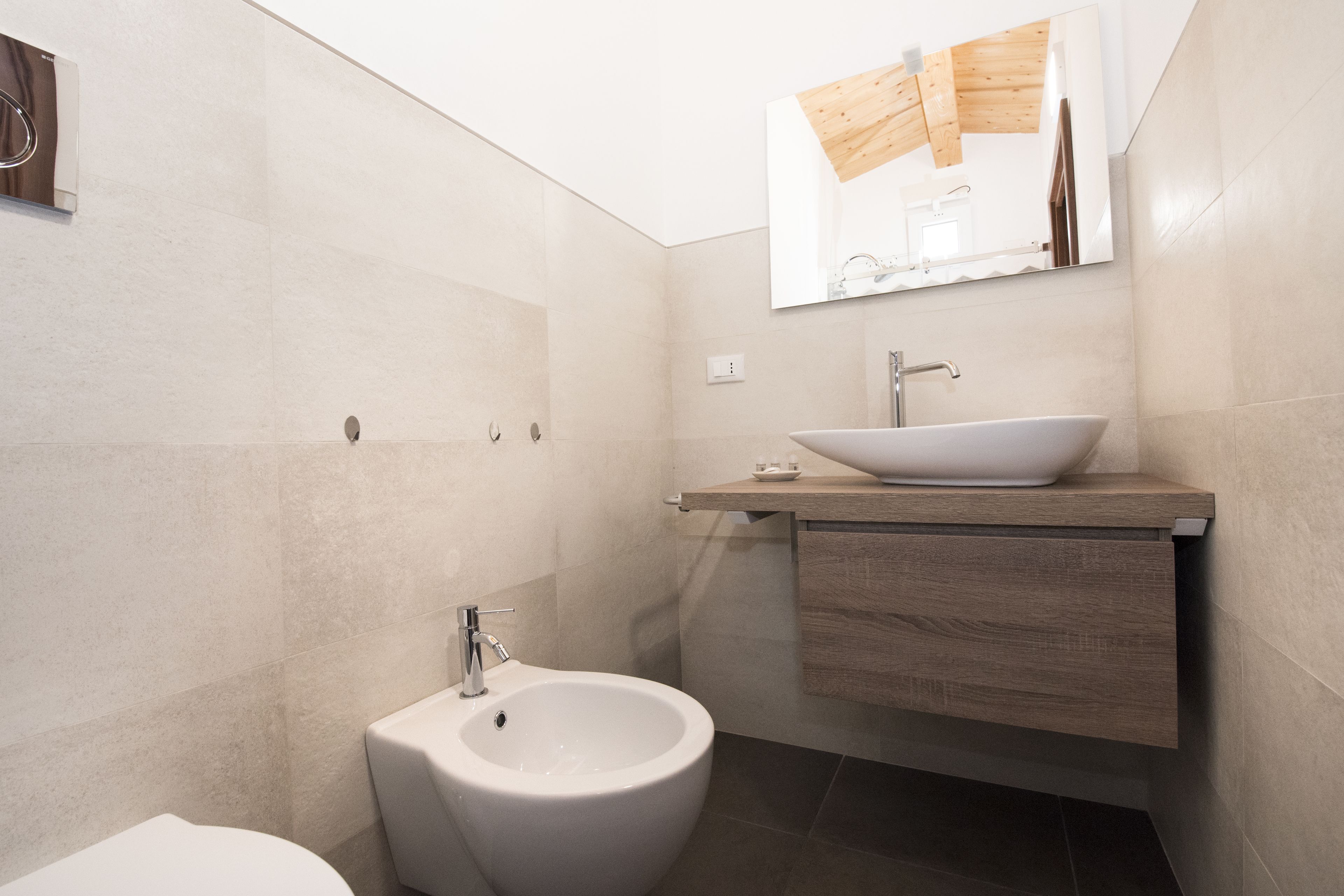 A modern bathroom with a bidet, a sink, and a mirror.