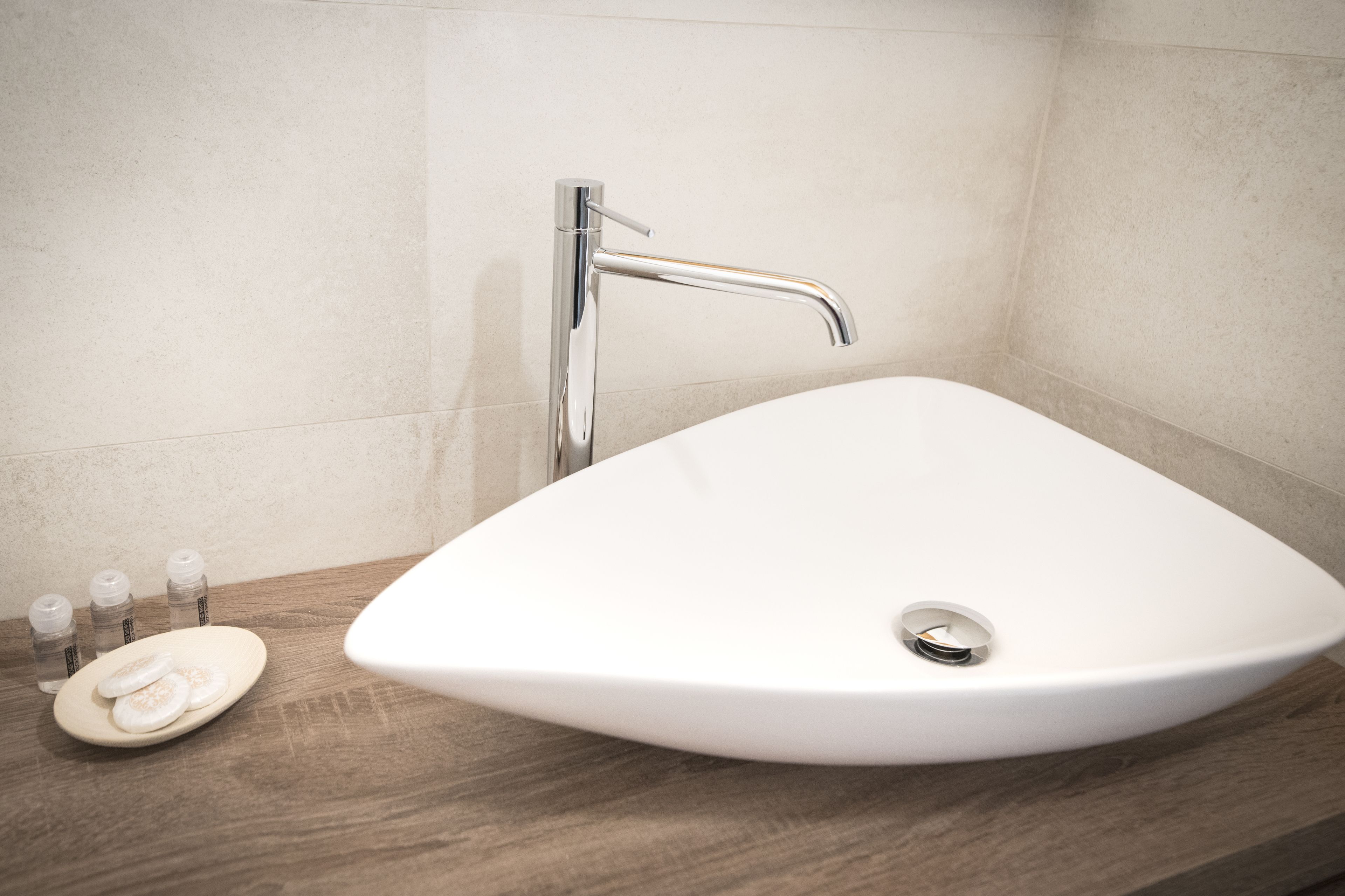 Un baño con lavamanos blanco, un grifo moderno y una encimera de madera.